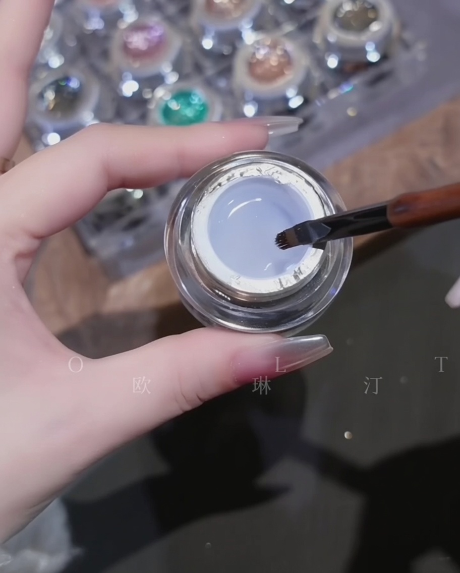 Pinceau appliquant un gel de construction transparent et visqueux sur un ongle chromé.