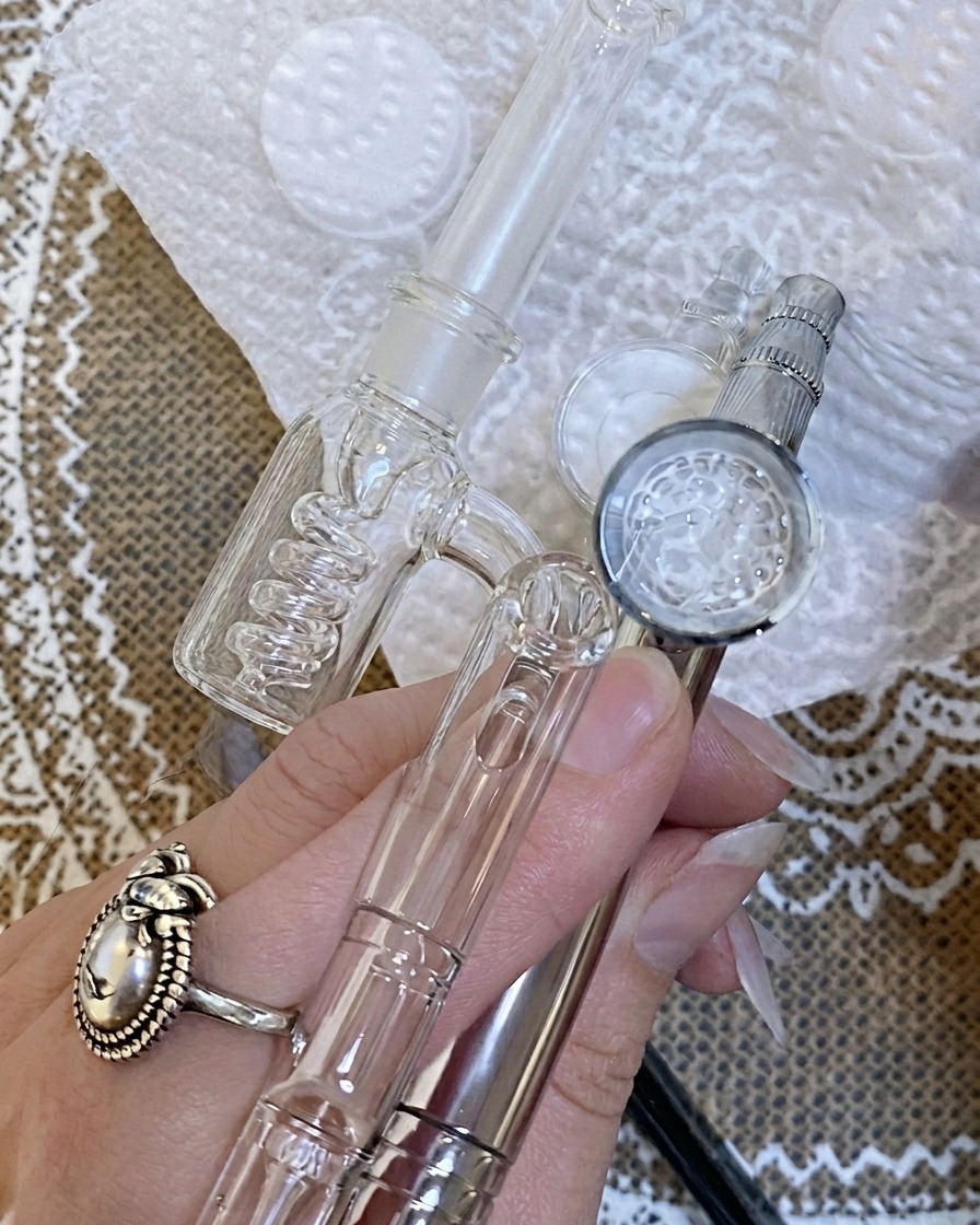 Utilisation dun aérographe pour appliquer une fine brume de couleur sur un ongle positionné sur une surface blanche.