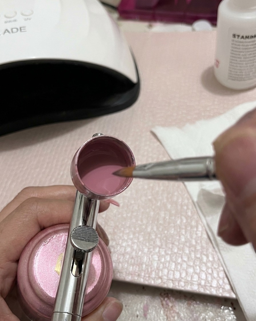 Gros plan sur un outil de mélange métallique remuant du gel rose à lintérieur dune coupelle daérographe.