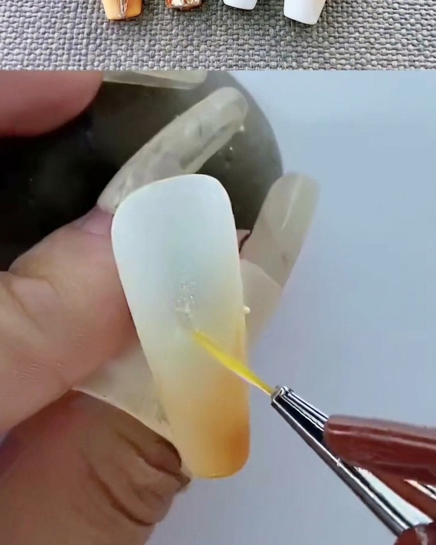 Une pince déposant un emblème métallique doré sur une surface de gel non catalysée.