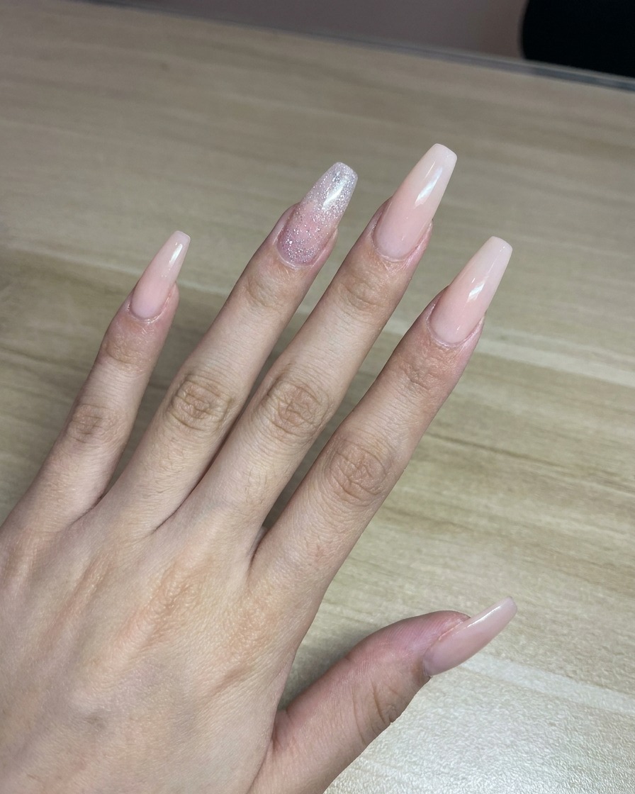 Un technicien pulvérisant de la peinture rose depuis un aérographe sur une feuille de papier blanc comme test avant lapplication sur les ongles.