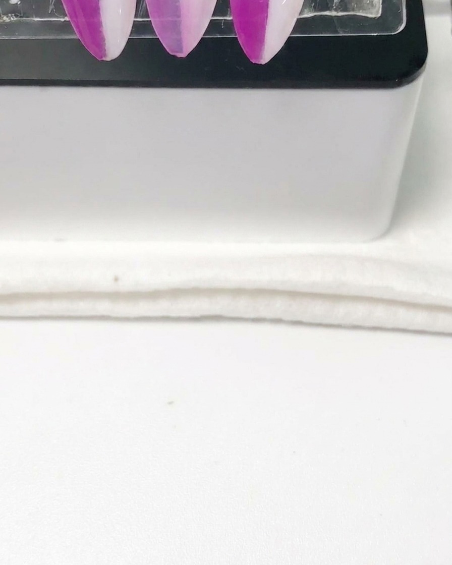 Une pipette versant un liquide diluant transparent dans le godet métallique dun aérographe.