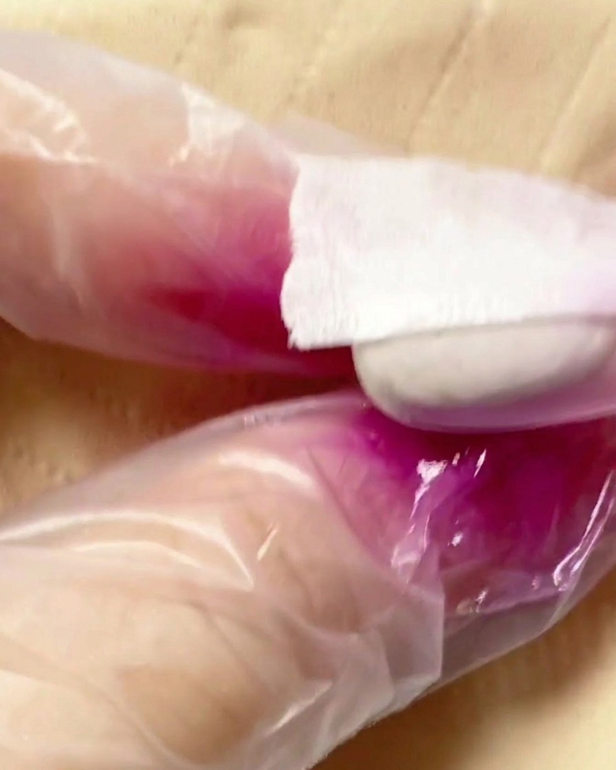 Un aérographe appliquant une brume de pigment violet sur la seconde moitié de la capsule.