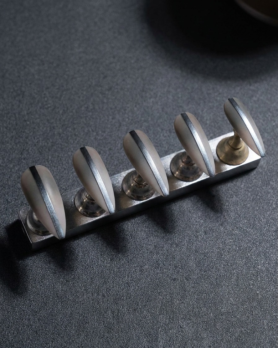 Gros plan dun support métallique avec cinq faux ongles, focus sur laffinage des bords latéraux avec une lime.