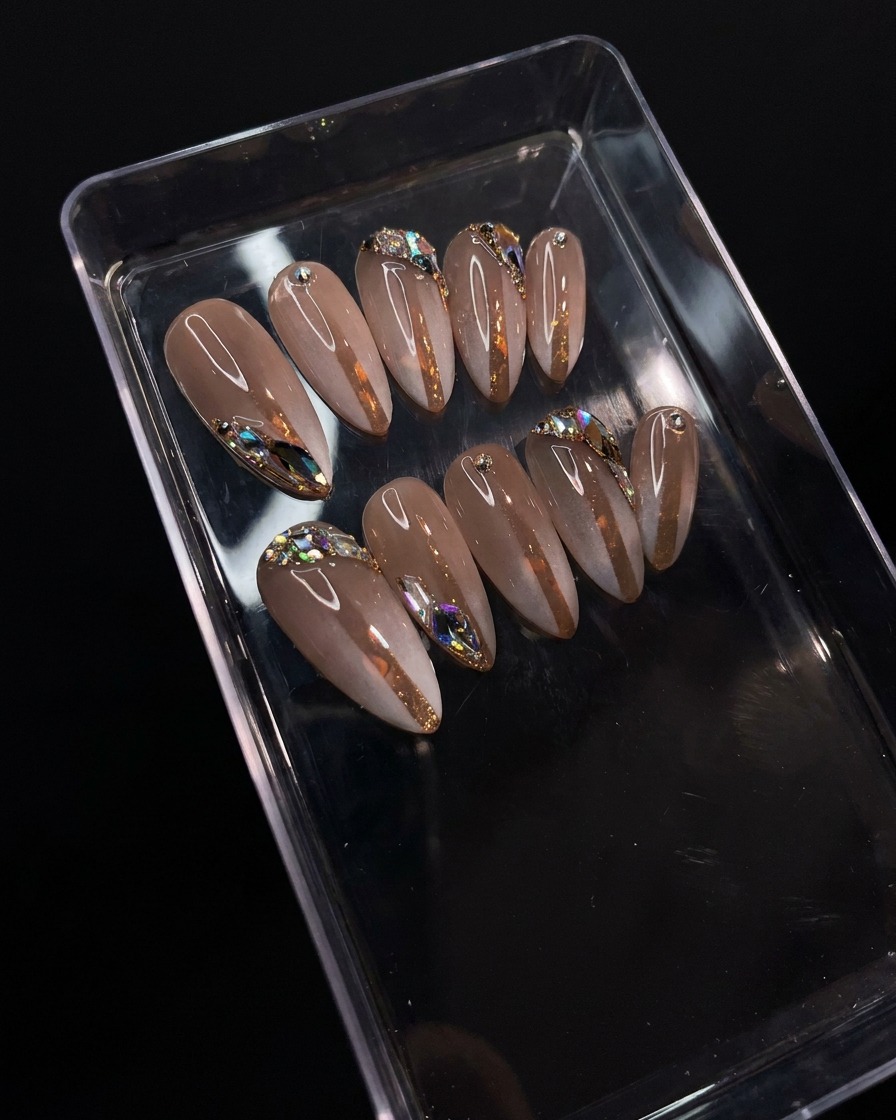 Un pinceau appliquant un top coat brillant et transparent sur le design en dégradé et strass.
