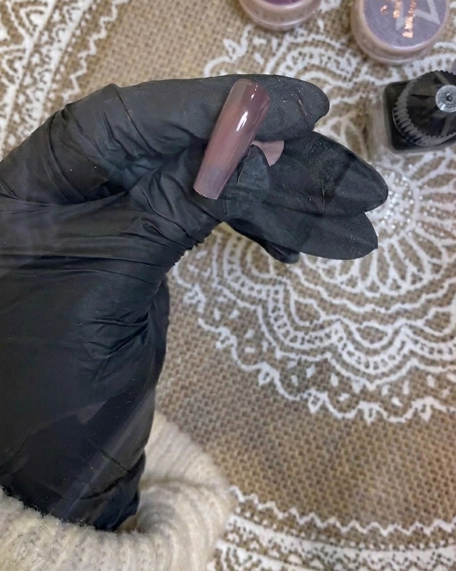 Utilisation dun aérographe pour appliquer un léger dégradé blanc sur le bord dun ongle violet foncé.