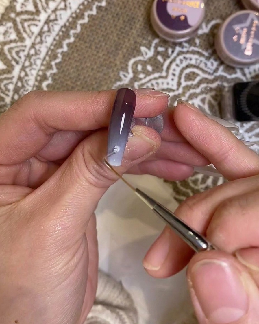 Un pinceau de détail appliquant soigneusement de la couleur près de la zone des cuticules.