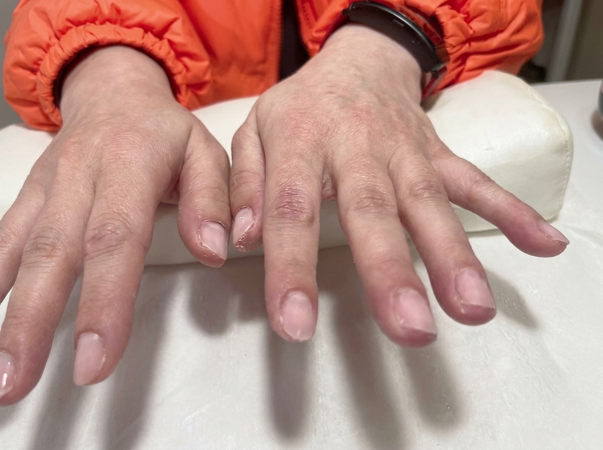 Gros plan sur un outil plaçant un minuscule charm en forme de nœud doré sur la surface dun ongle.