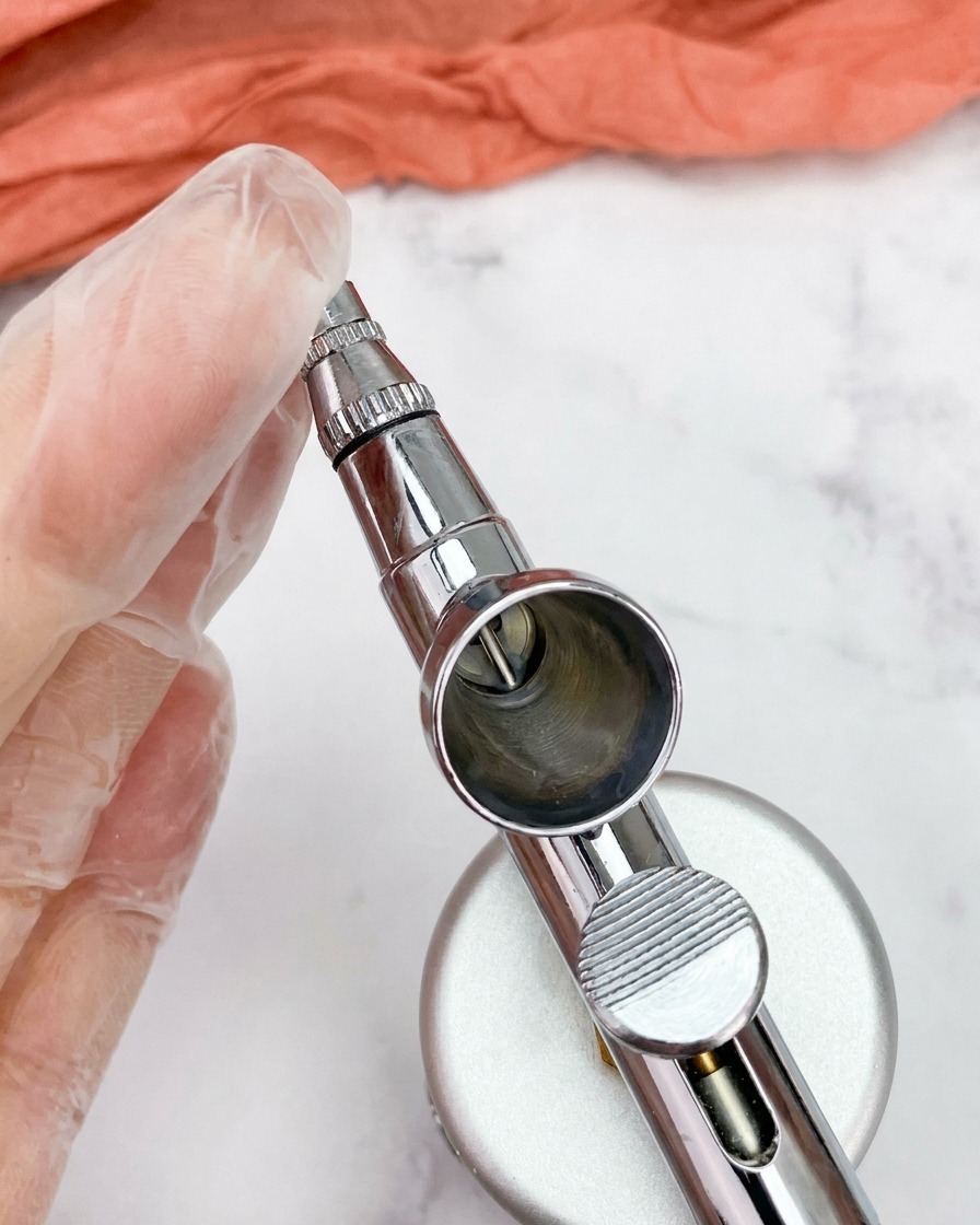 Gros plan sur un godet daérographe métallique propre et vide fixé sur le pistolet.