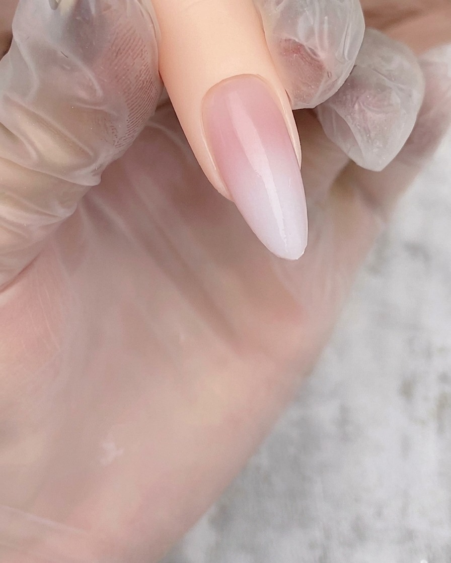 Une capsule amande montrant un dégradé blanc aérographe doux et transparent sur une base nude.