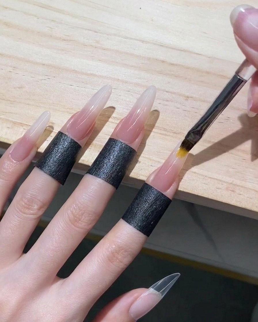 Un pinceau à ombré fondant le gel nude vers le haut dans le gel blanc humide pour créer un dégradé sans transition visible.