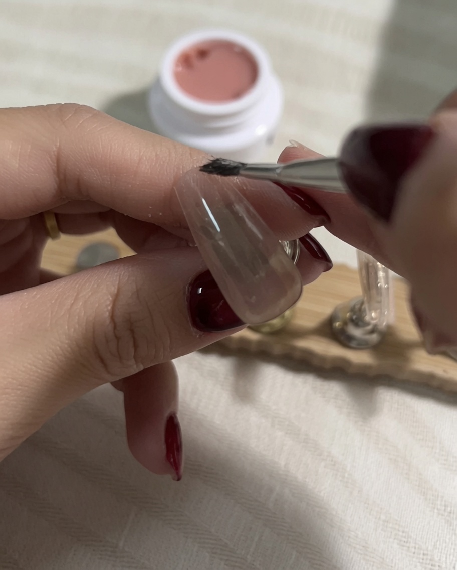 Prélever une nuance de vernis gel nude plus claire sur un pinceau plat après la catalyse.
