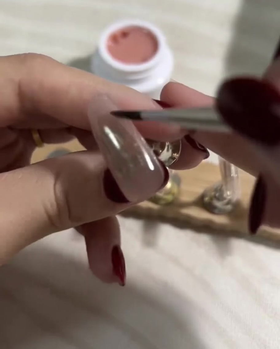 Brosser une couche lisse de vernis gel nude clair sur la base foncée déjà catalysée.