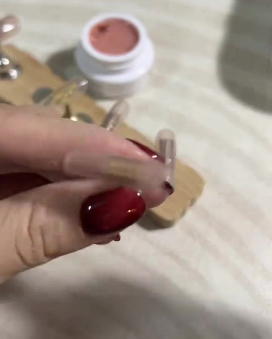 Gros plan sur une main utilisant une lingette non pelucheuse imbibée de cleaner pour nettoyer les ongles.