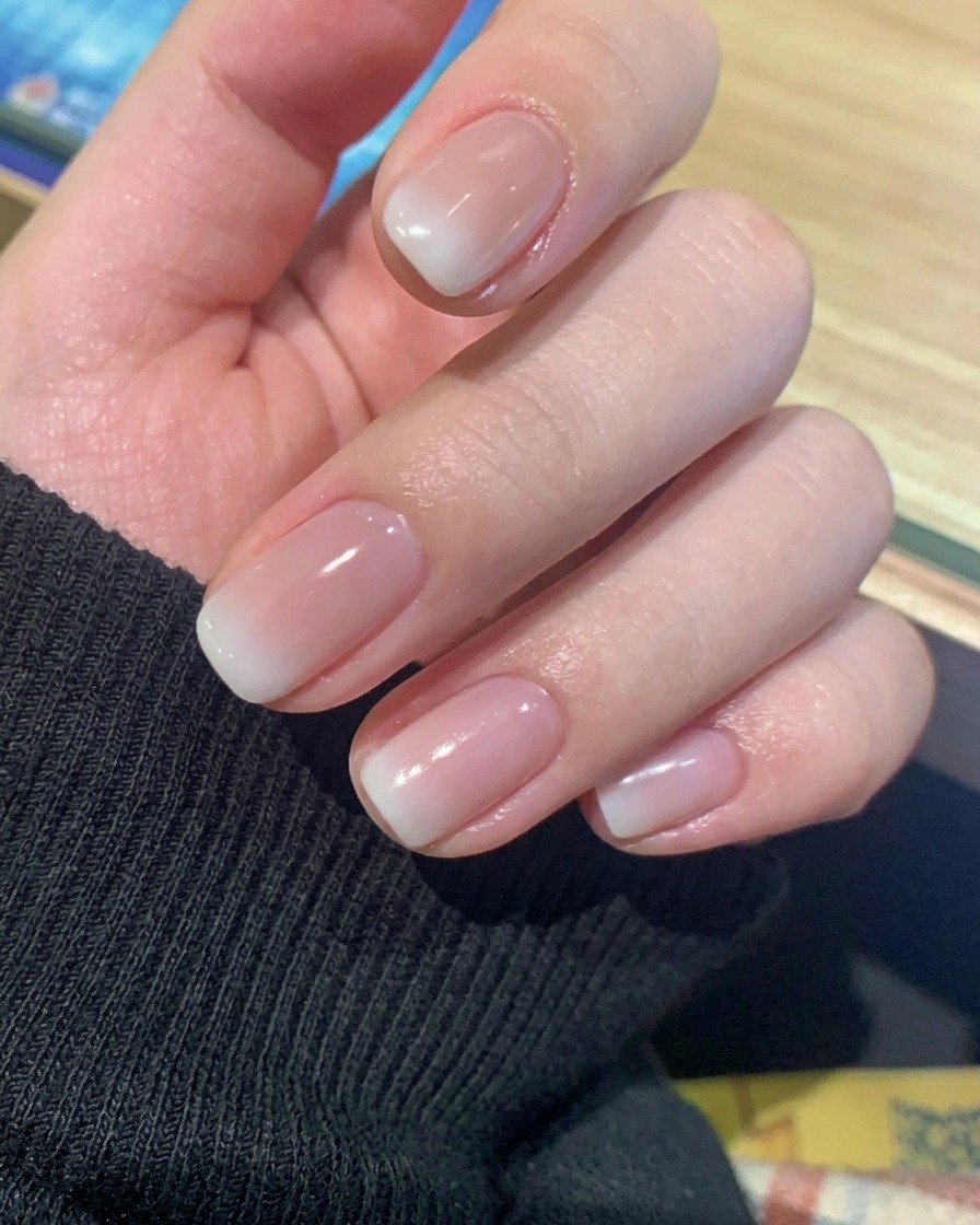 Gros plan dune main reposant dans une lampe à ongles UV/LED professionnelle, les ongles éclairés par la lumière.