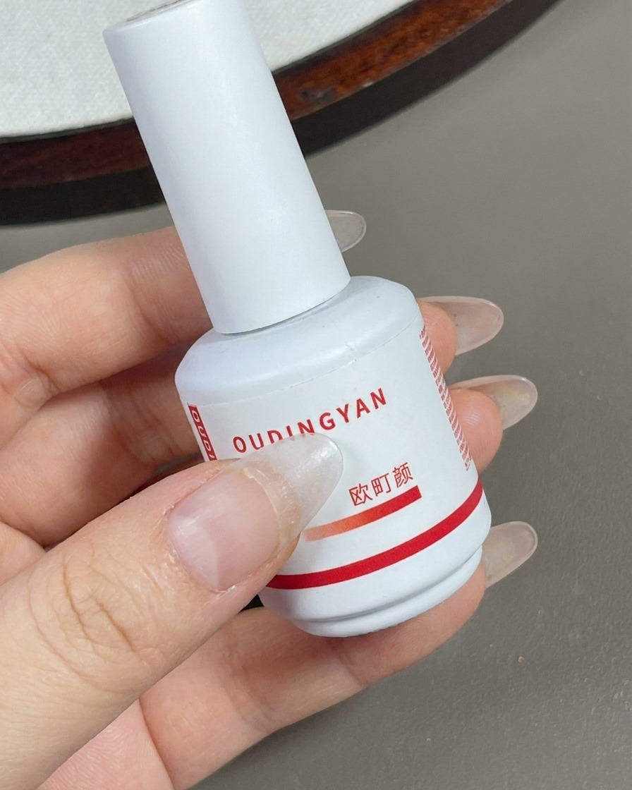 Un pinceau appliquant une couche de gel nude contour transparent sur toute la surface de longle.