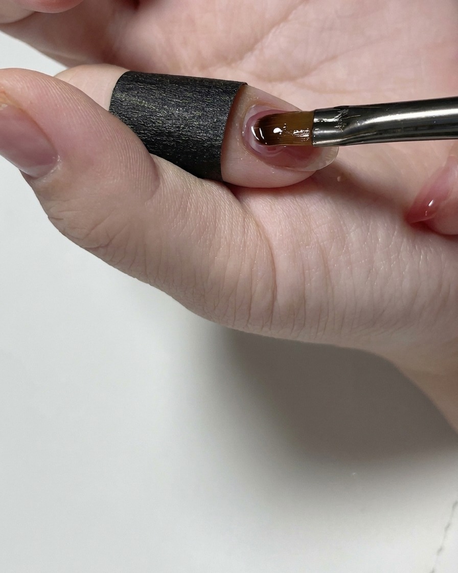 Un pinceau fin de précision lissant le gel de construction transparent près de la cuticule.