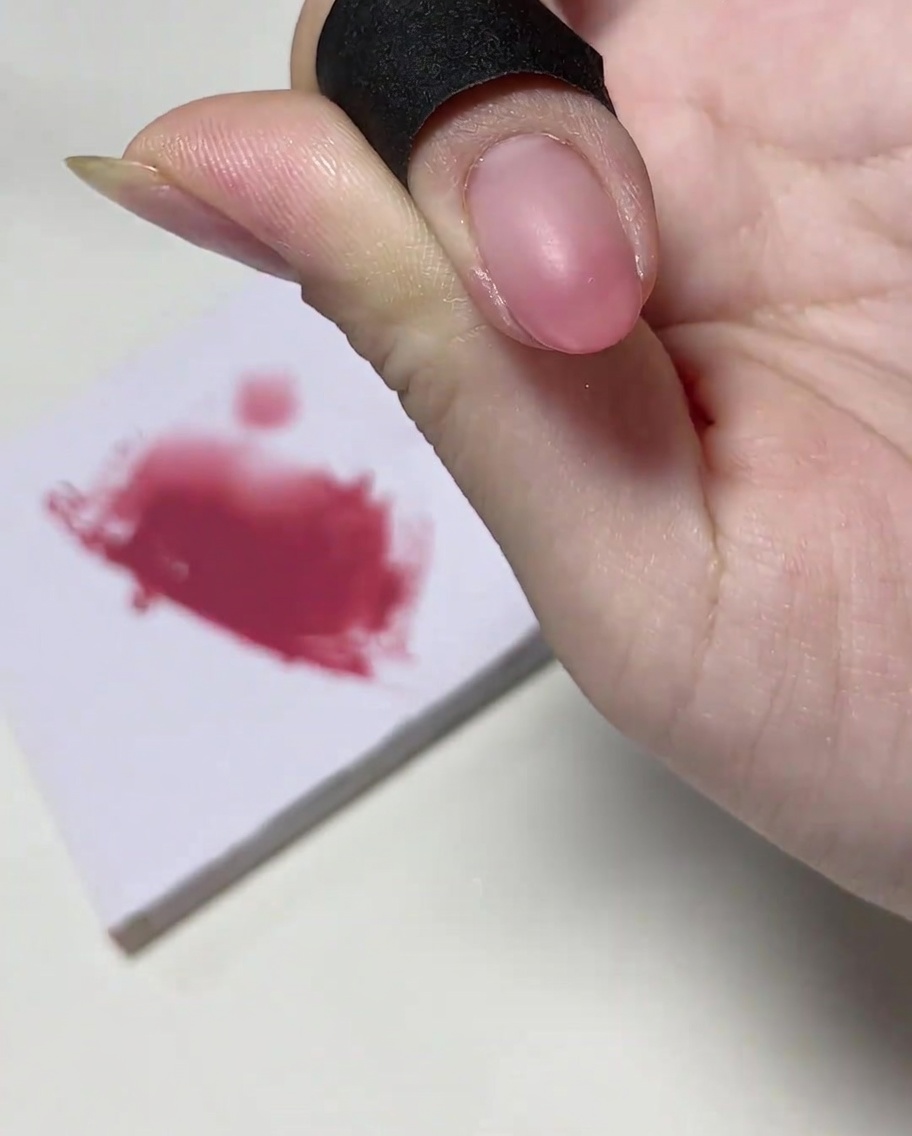Un pinceau à ongles ajoutant une quantité concentrée de gel rose sur le bout de longle.