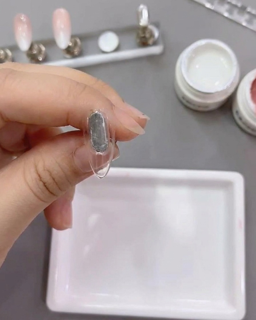 Un pinceau plat applique du gel blanc numéro 79 sur le bout dun ongle naturel.