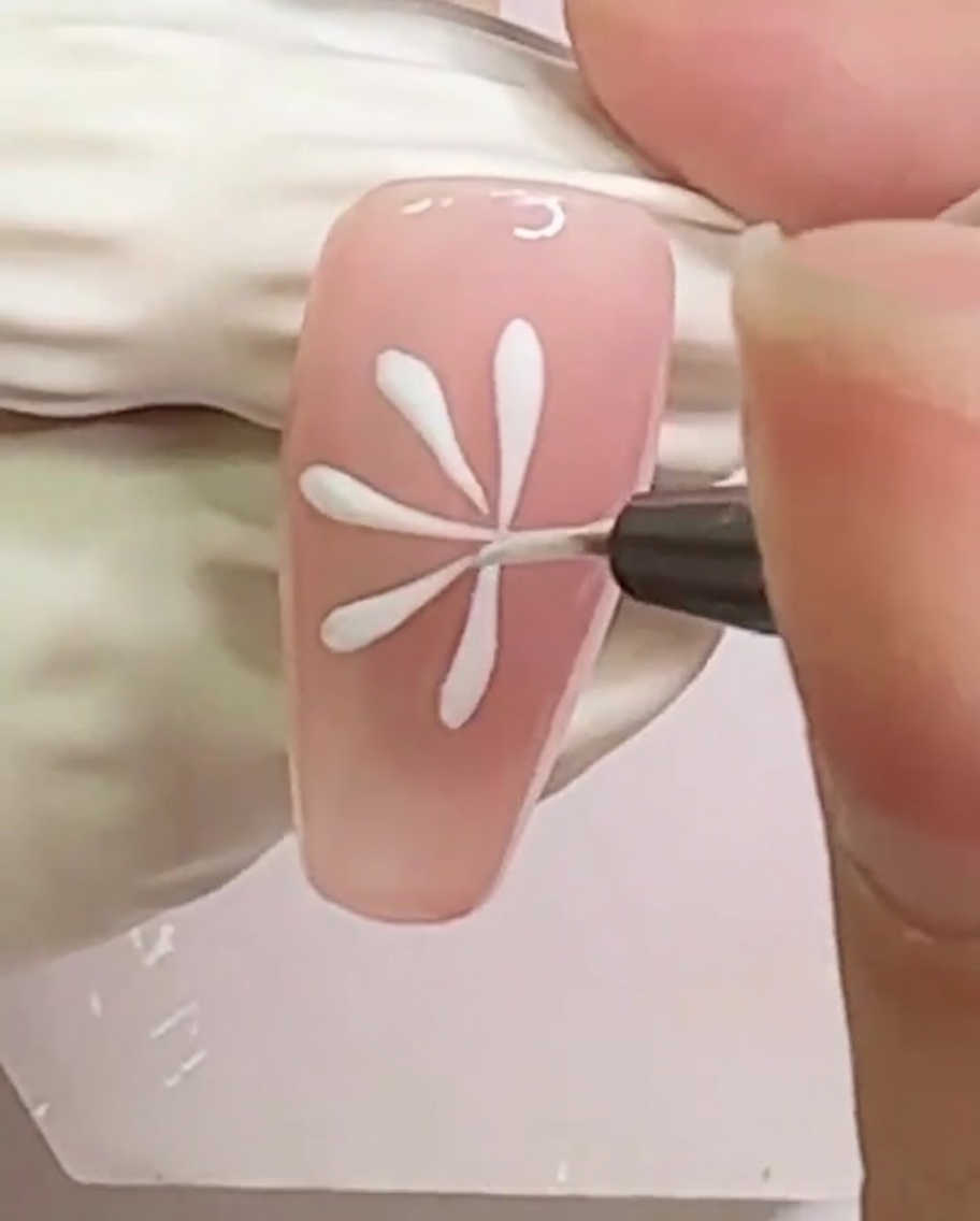 Un ongle présentant un motif dense de lignes blanches radiales pour la marguerite.