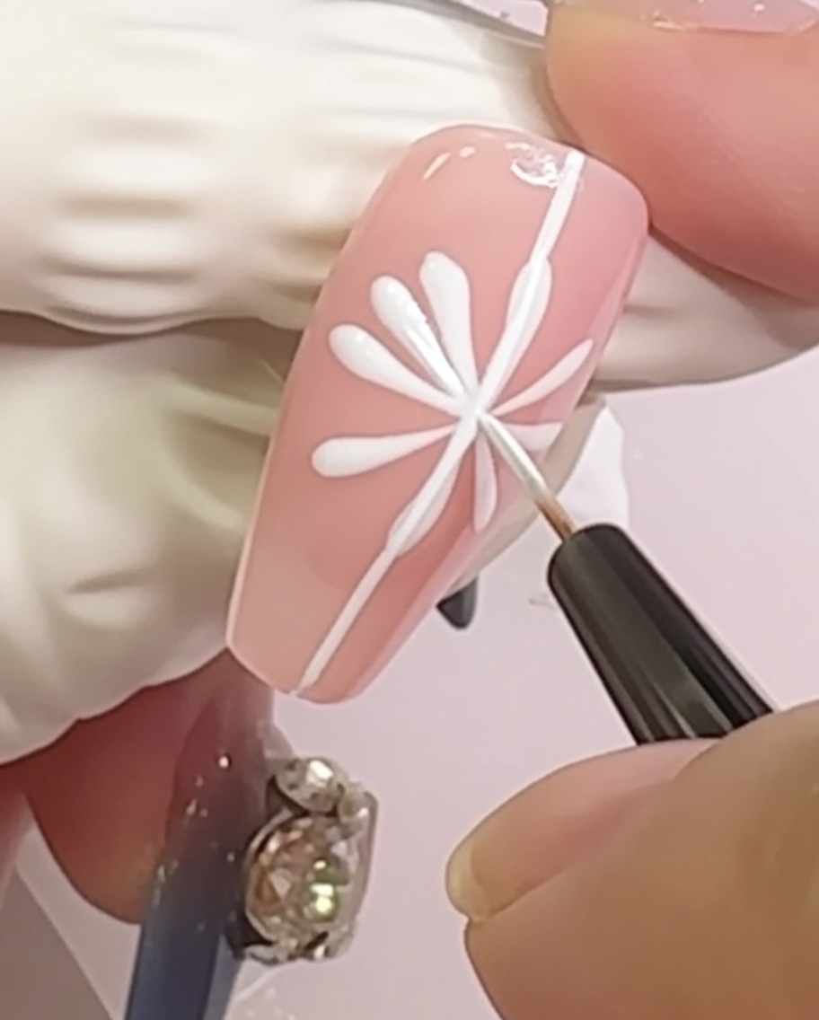Un ongle montrant une marguerite avec de petites formes de pétales arrondies ajoutées aux extrémités des lignes radiales.