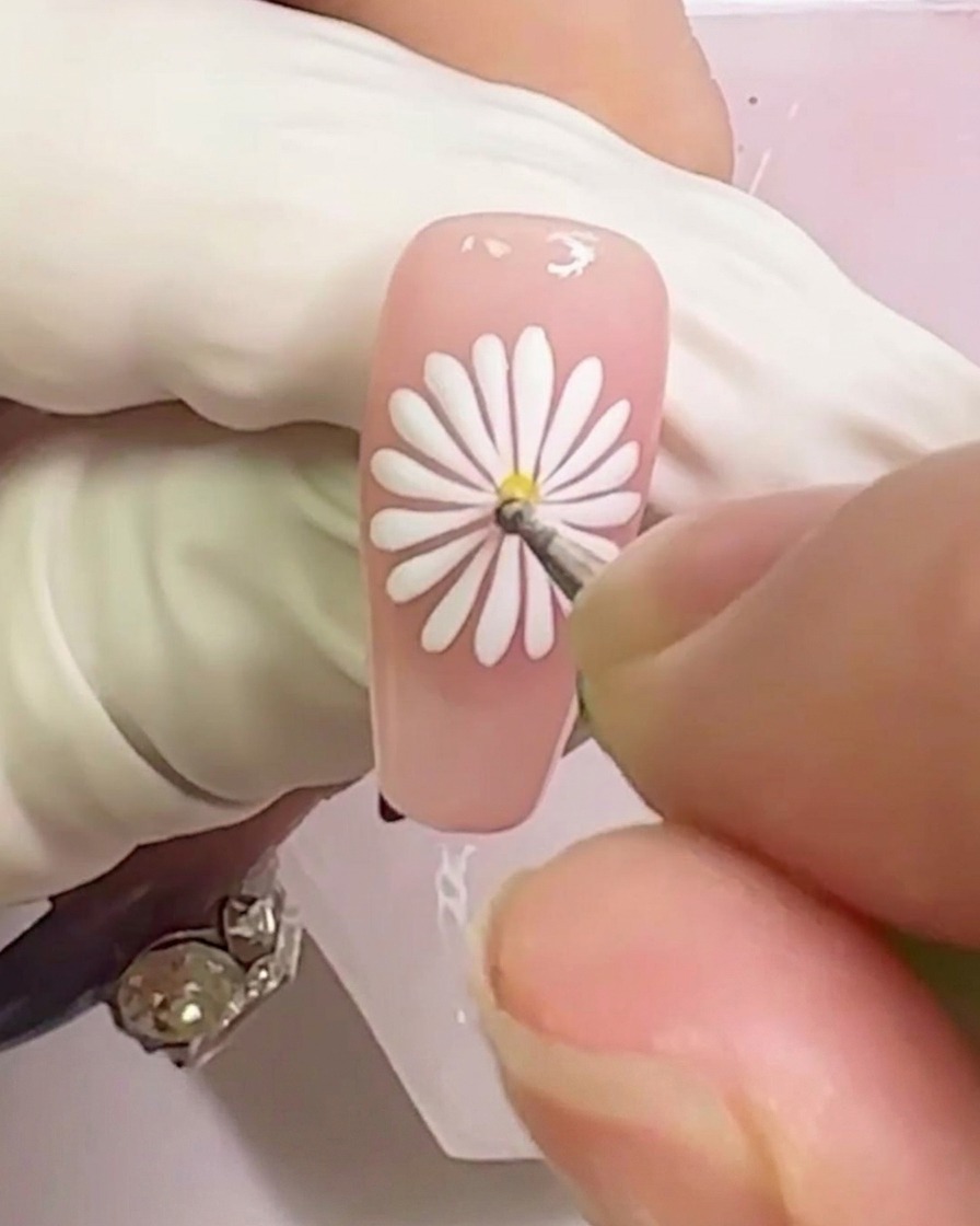 Gros plan montrant un point de gel jaune appliqué au centre du motif de marguerite blanche.