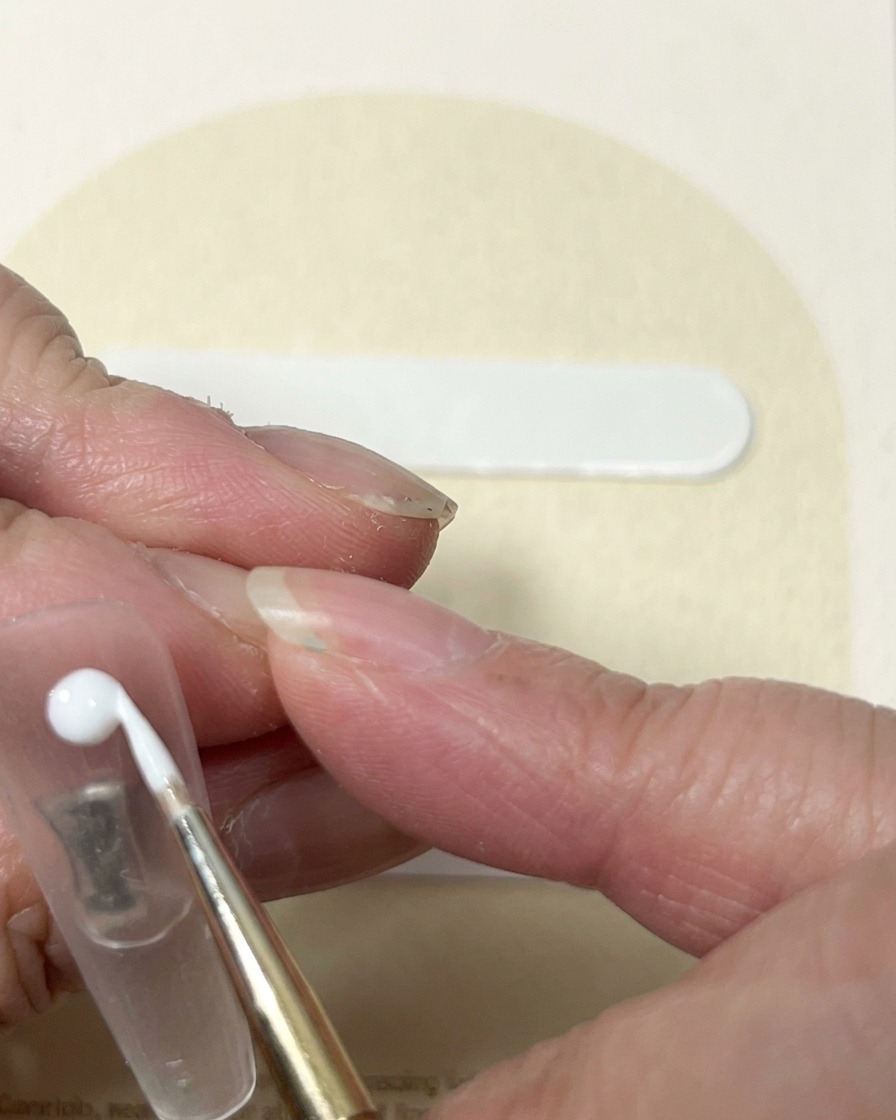 Un pinceau liner tirant du gel blanc depuis un point central pour créer laspect dun bouton de rose.