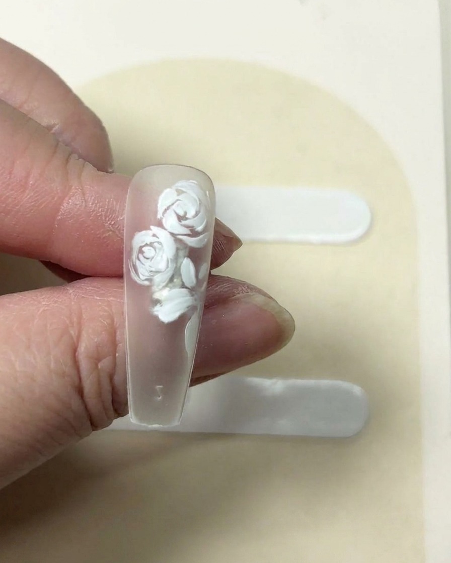 Un mouchoir pressé sur une fleur blanche à cinq pétales fraîchement peinte sur un ongle pour adoucir la texture.