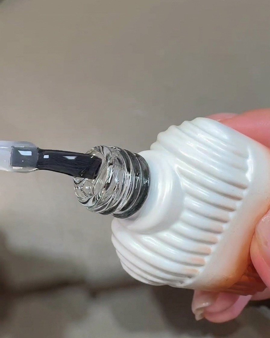 Un pinceau appliquant une couche claire et brillante de blooming gel sur une surface dongle préparée.