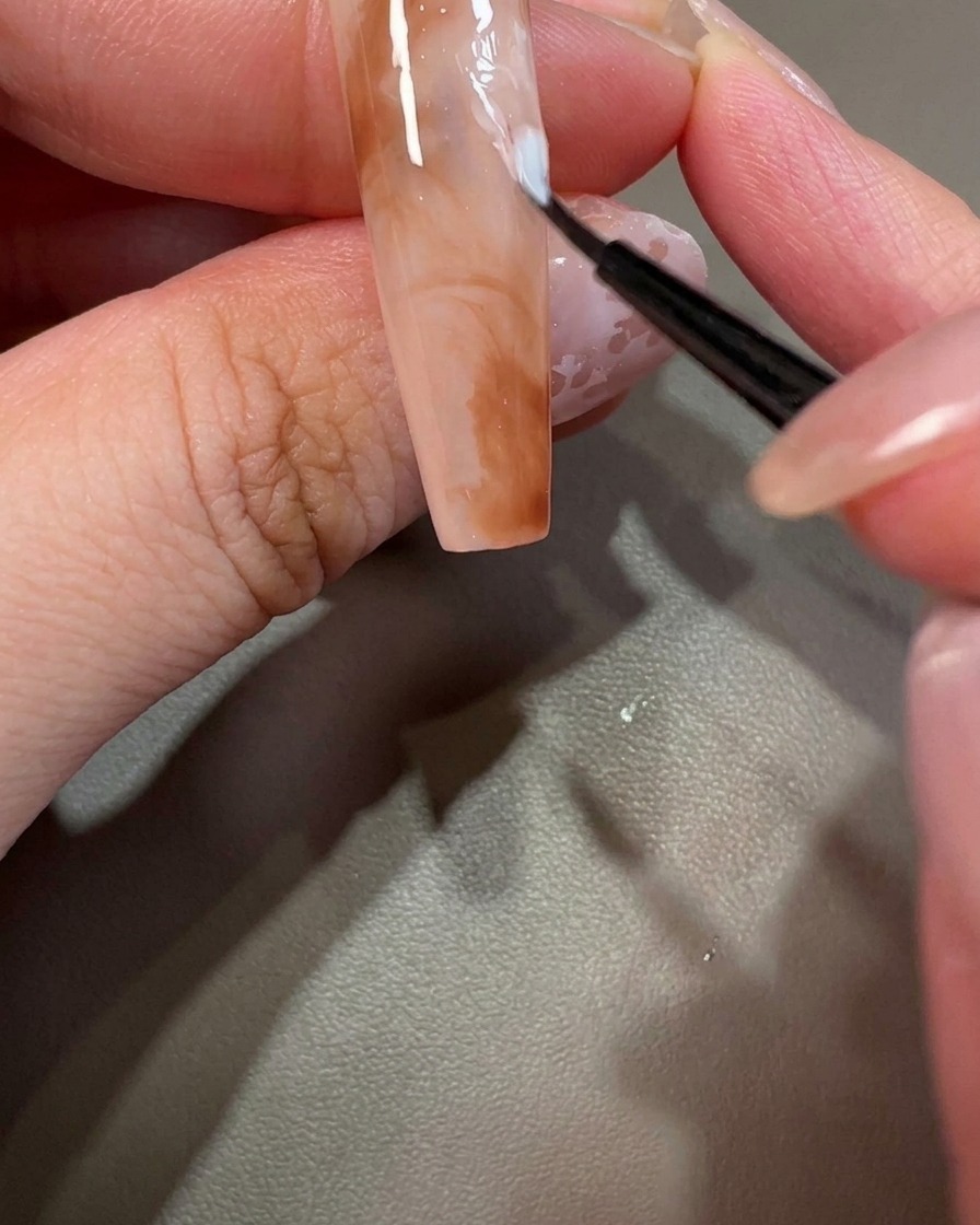 Gros plan dun ongle décoré avec un minuscule point de vernis gel blanc.