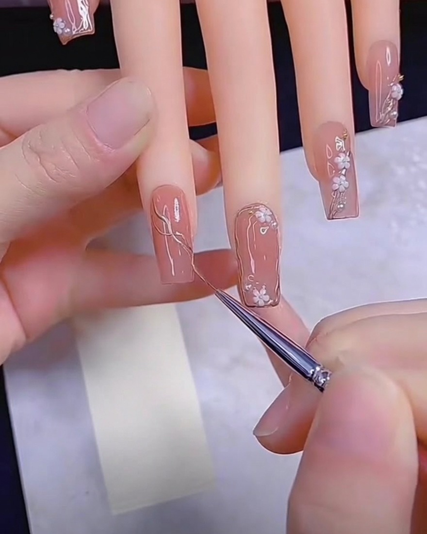Un pinceau de détail appliquant du gel métallique sur un ongle nude.