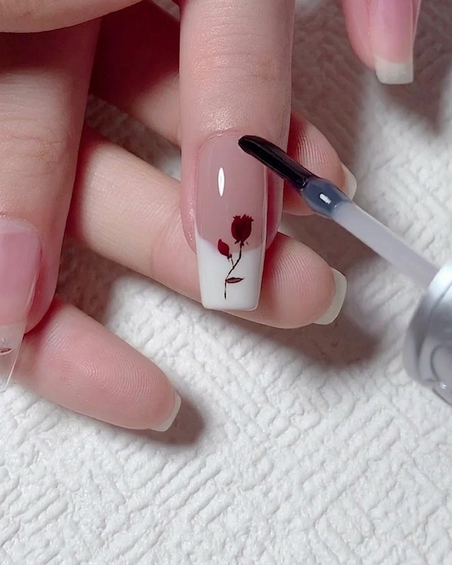 Un pinceau de vernis gel appliquant une couche lisse de gel de construction transparent sur un nail art rose peint.