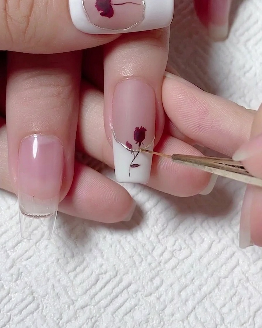 Gros plan montrant un pinceau liner appliquant une ligne précise de top coat sur un accent métallique couleur champagne sur un ongle French.