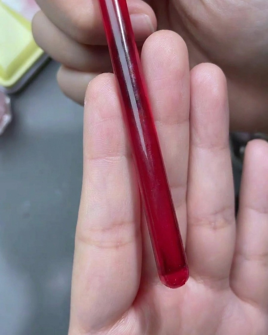 Un pinceau liner fin dessinant des contours de rose blanche sur un ongle au fini mat.