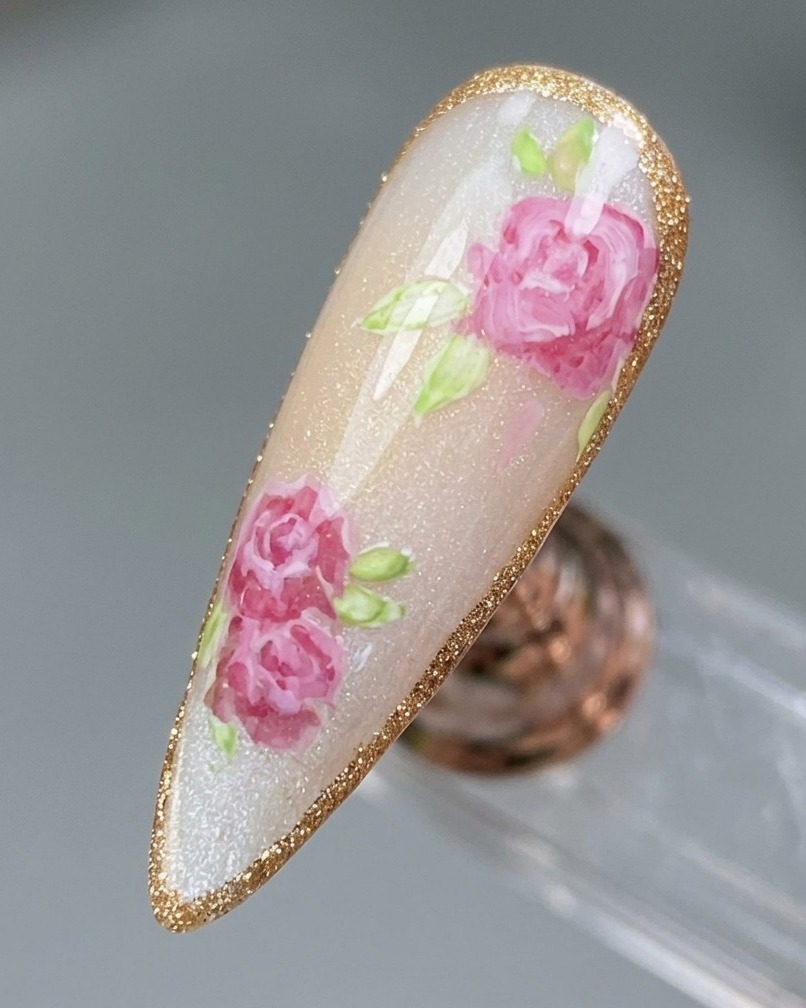 Gros plan sur un design dongle rose fini étant tracé avec une bordure délicate et scintillante en gel platine.