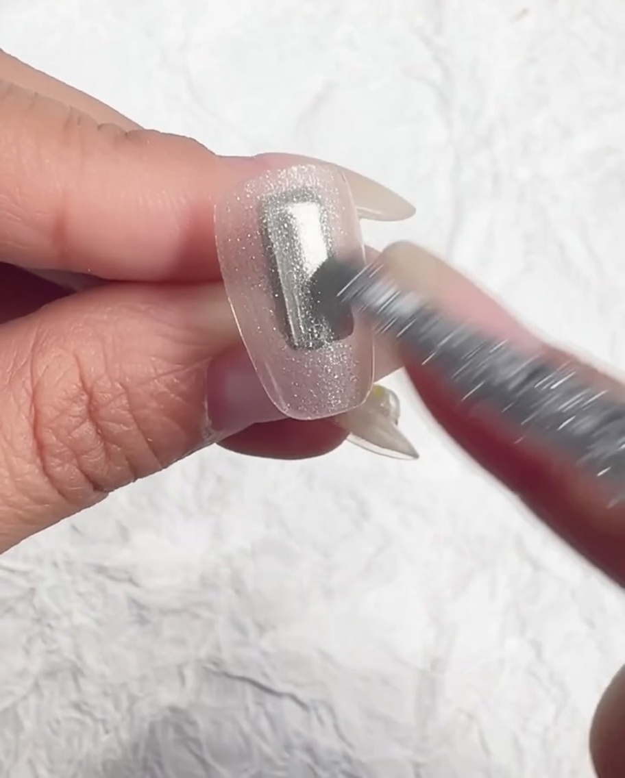 Un pinceau égalisant le gel translucide sur longle.