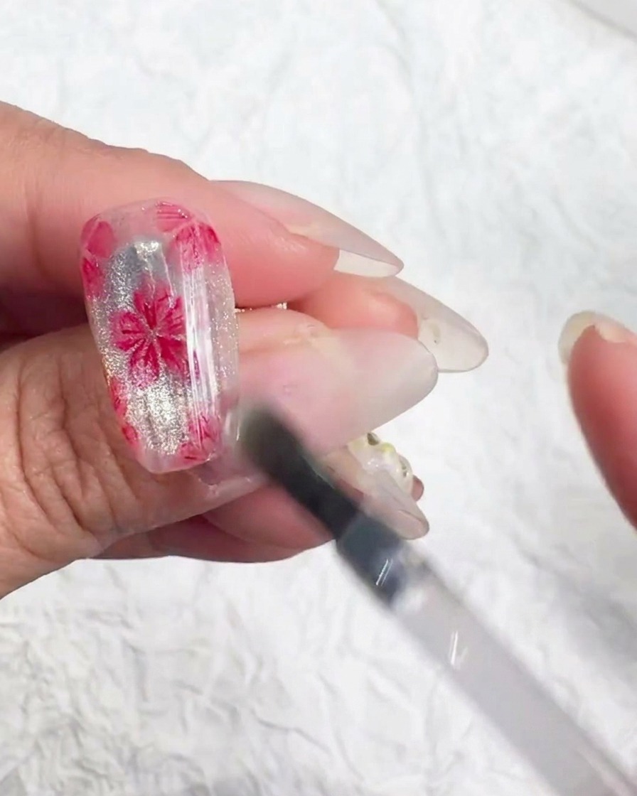 Un outil appliquant des flocons irisés au centre dune fleur peinte.