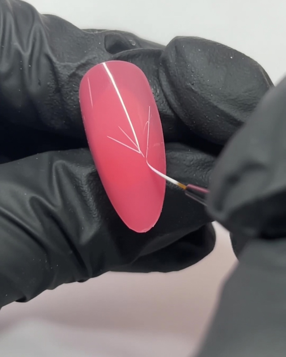 Gros plan sur un ongle rose montrant des lignes blanches qui sentrecroisent pour former un guide en Y.