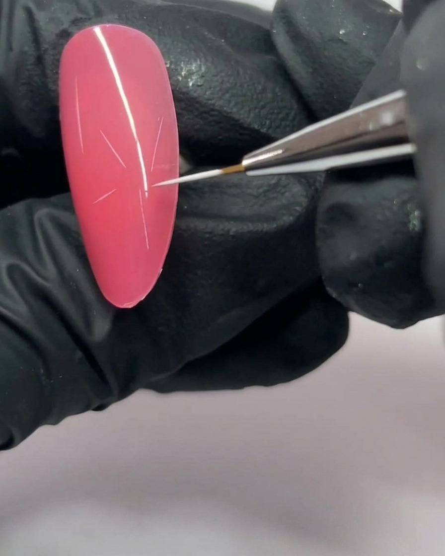 Gros plan sur un ongle rose avec une structure en étoile à cinq branches dessinée en blanc.