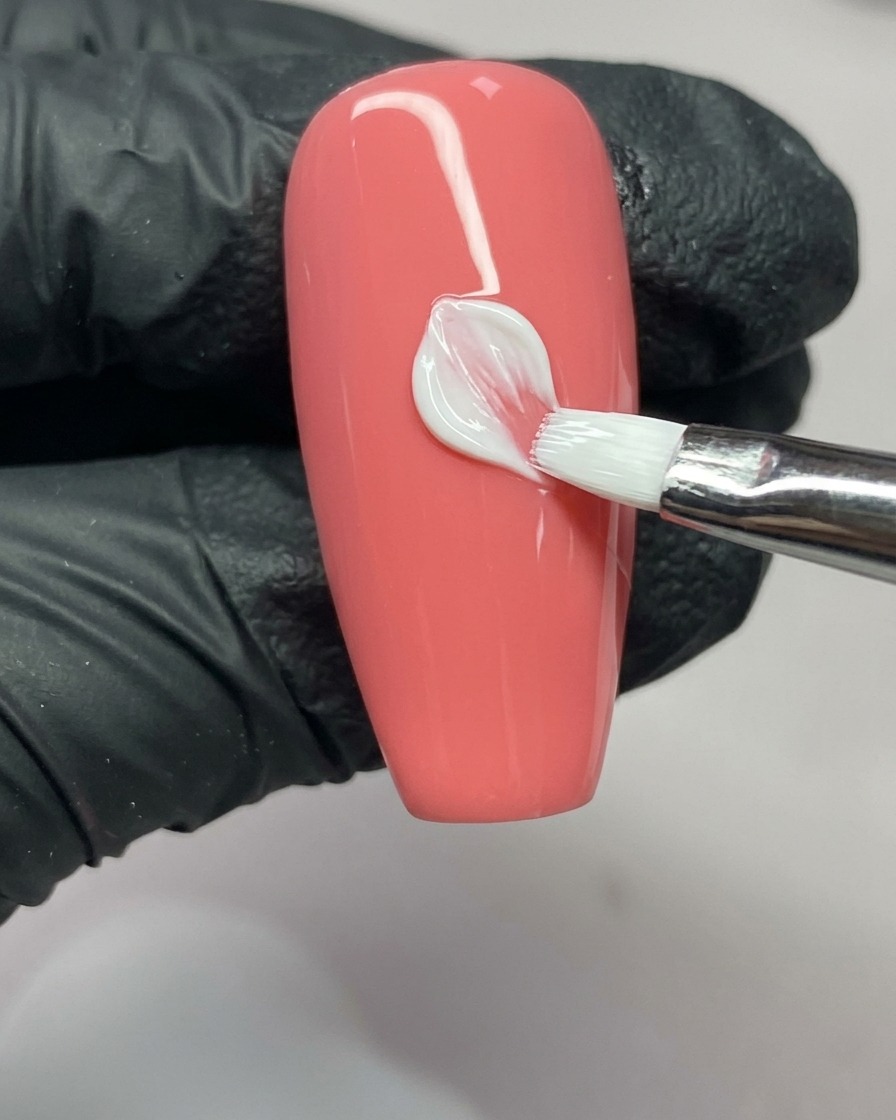Un pinceau de nail art complétant le côté droit dun pétale, montrant la forme en V à lextrémité.