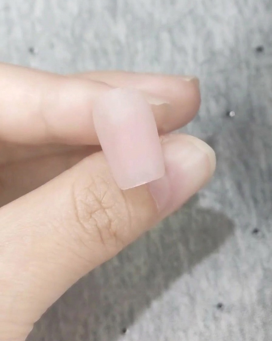Gros plan dun ongle parfaitement lisse avec une finition rose blush mate givrée.