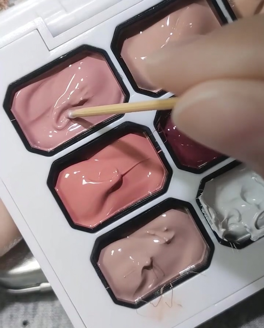 Un cure-dent en bois trempant dans une palette de gel rose cerisier opaque.