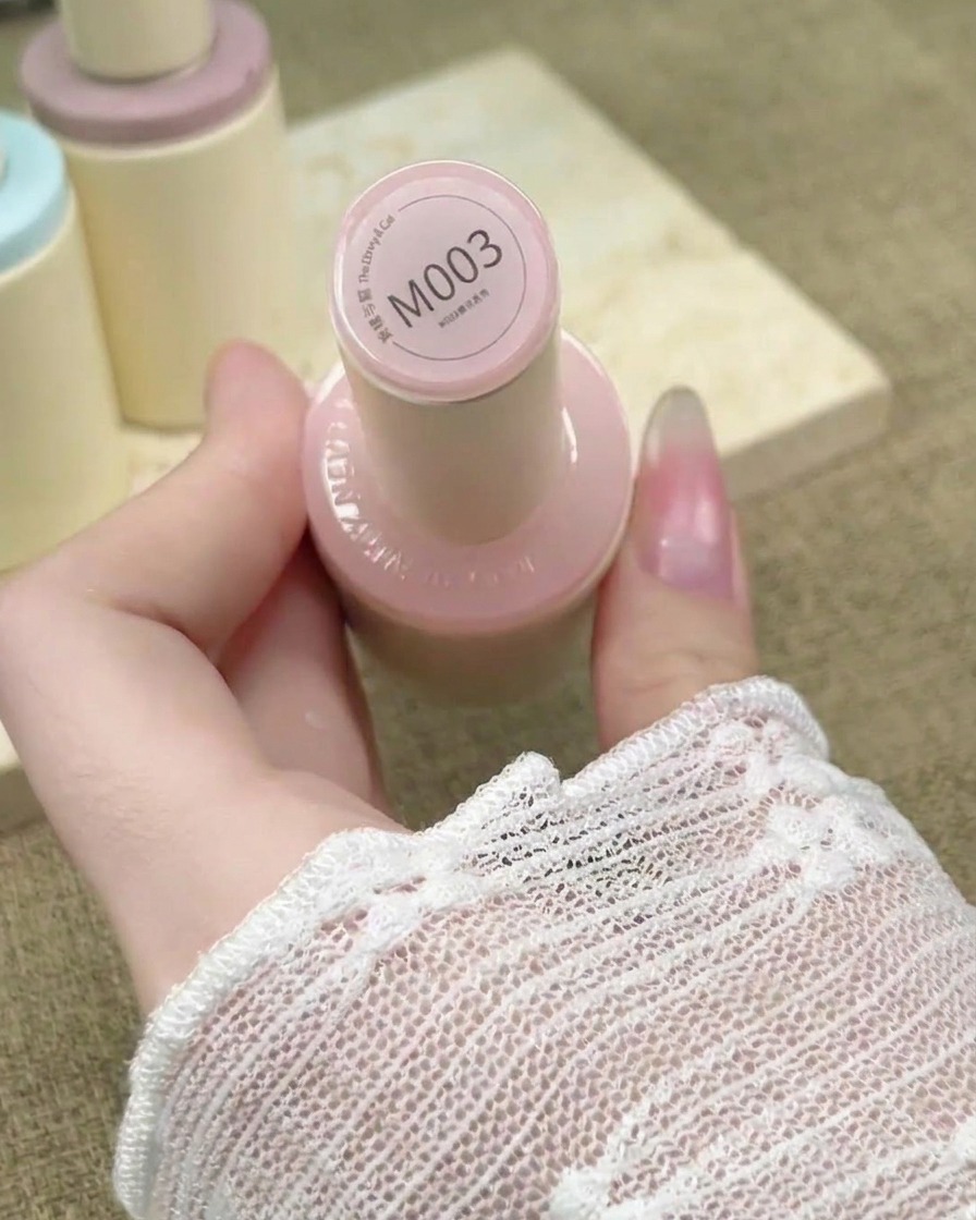 Un pinceau à ongles applique un vernis gel nude rosé transparent sur une extension dongle.