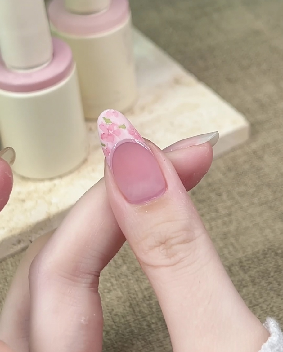 Un pinceau fin ajoute des petites feuilles vertes autour des fleurs roses.