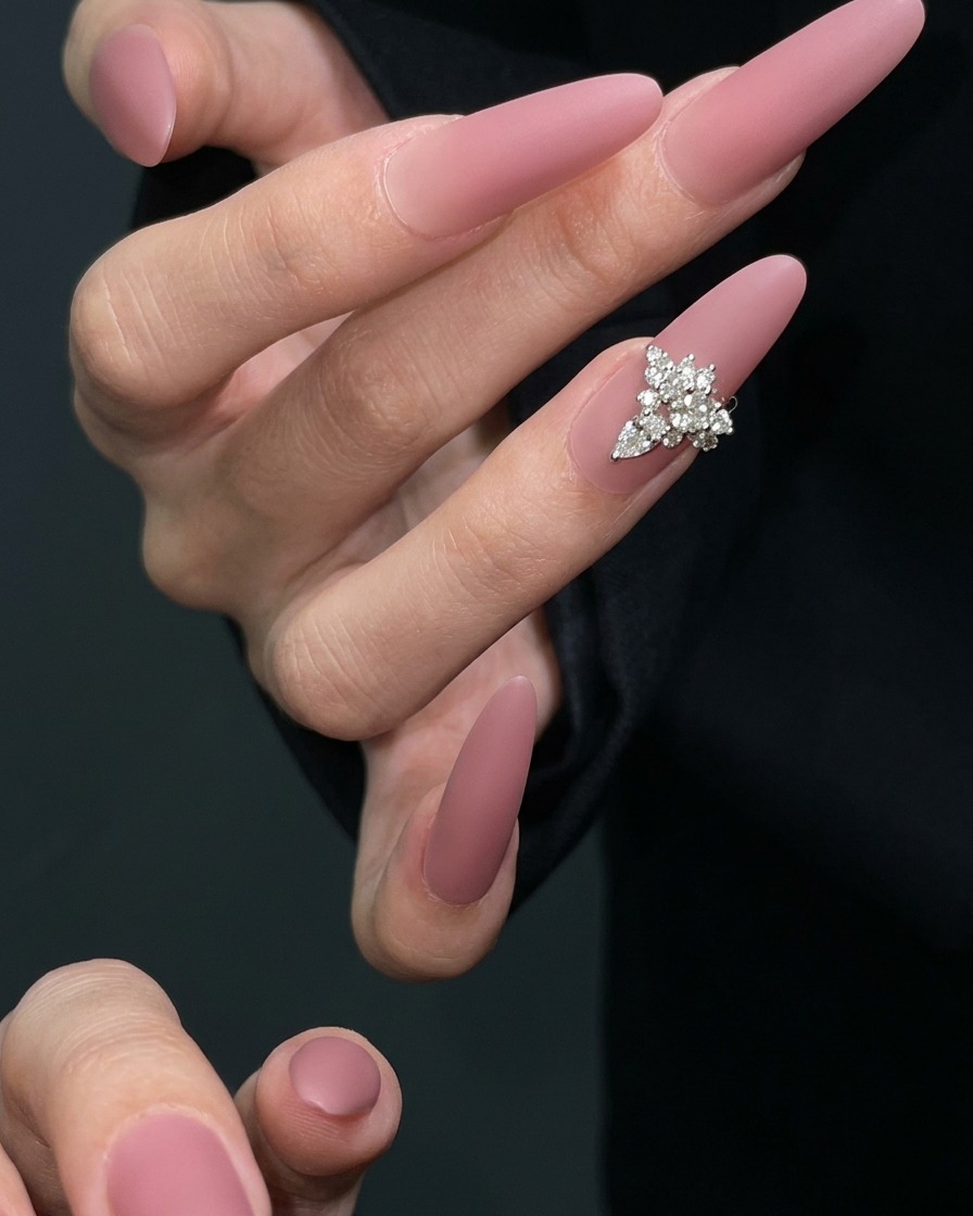 Un pinceau de nail art appliquant une couche de top coat mat sur un ongle mauve séché.