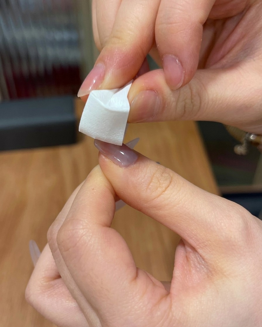 Gros plan dune éponge triangulaire utilisée pour tapoter du gel rose sur le bout dun ongle.