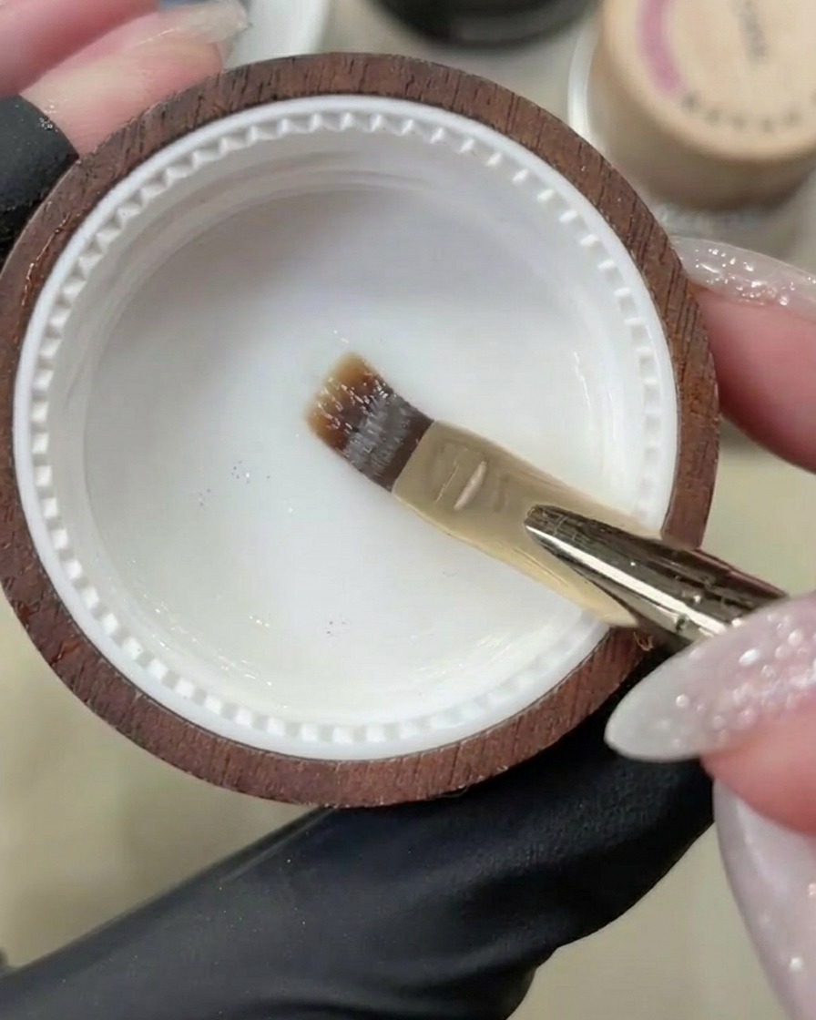 Un pinceau gel appliquant une base transparente sur un ongle naturel propre.