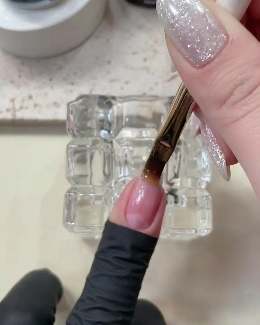 Une main placée dans une lampe UV/LED, avec la base en train de catalyser sur les ongles.