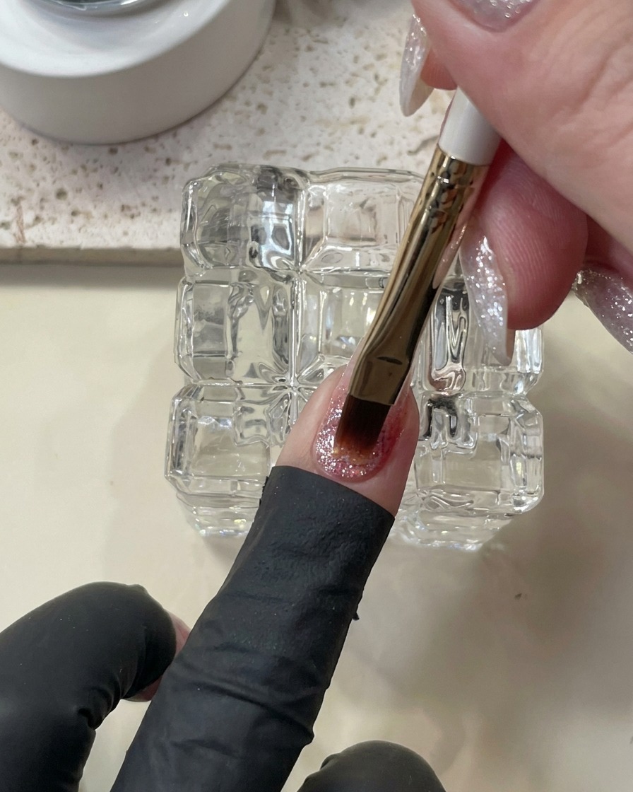 Un pinceau appliquant une goutte épaisse et autonivelante de gel de construction sur longle.