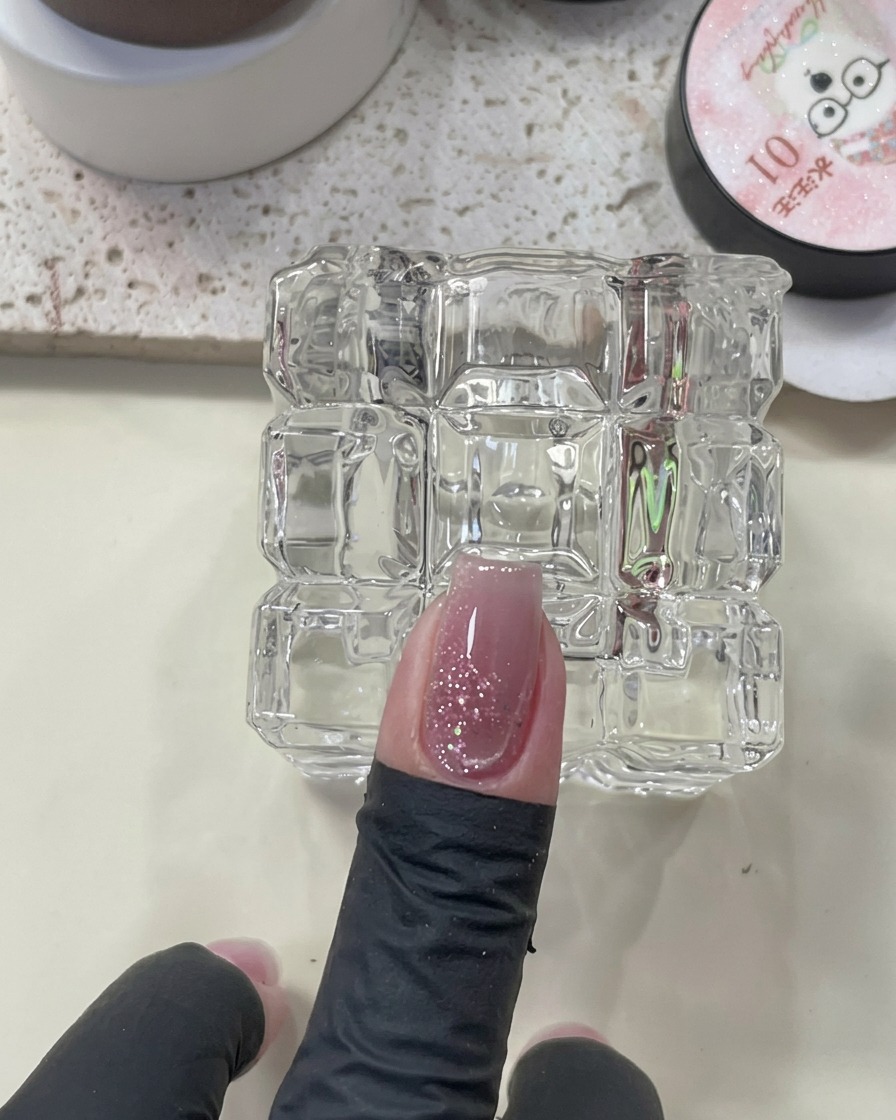 Un aimant positionné au-dessus dun ongle avec du vernis œil de chat humide pour attirer la ligne brillante.
